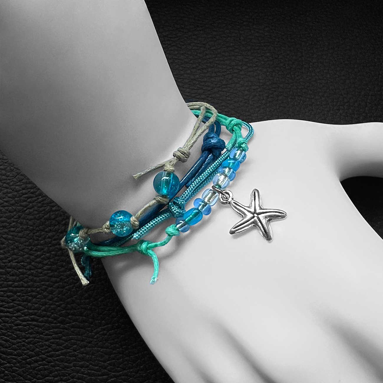 starfish bracelet stack with turquoise and blue cords, glass beads and silver-tone charm on a white mannequin wrist.