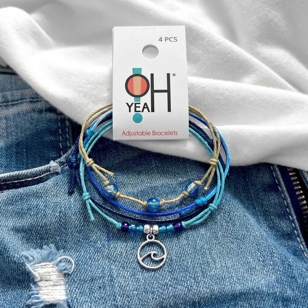 wave bracelet pack with blue cords, glass beads and silver-tone wave charm on faded denim with white fabric and O Yeah tag.