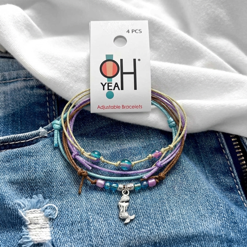mermaid bracelet stack with O Yeah tag on blue distressed denim, showing purple and turquoise cords and silver mermaid charm.