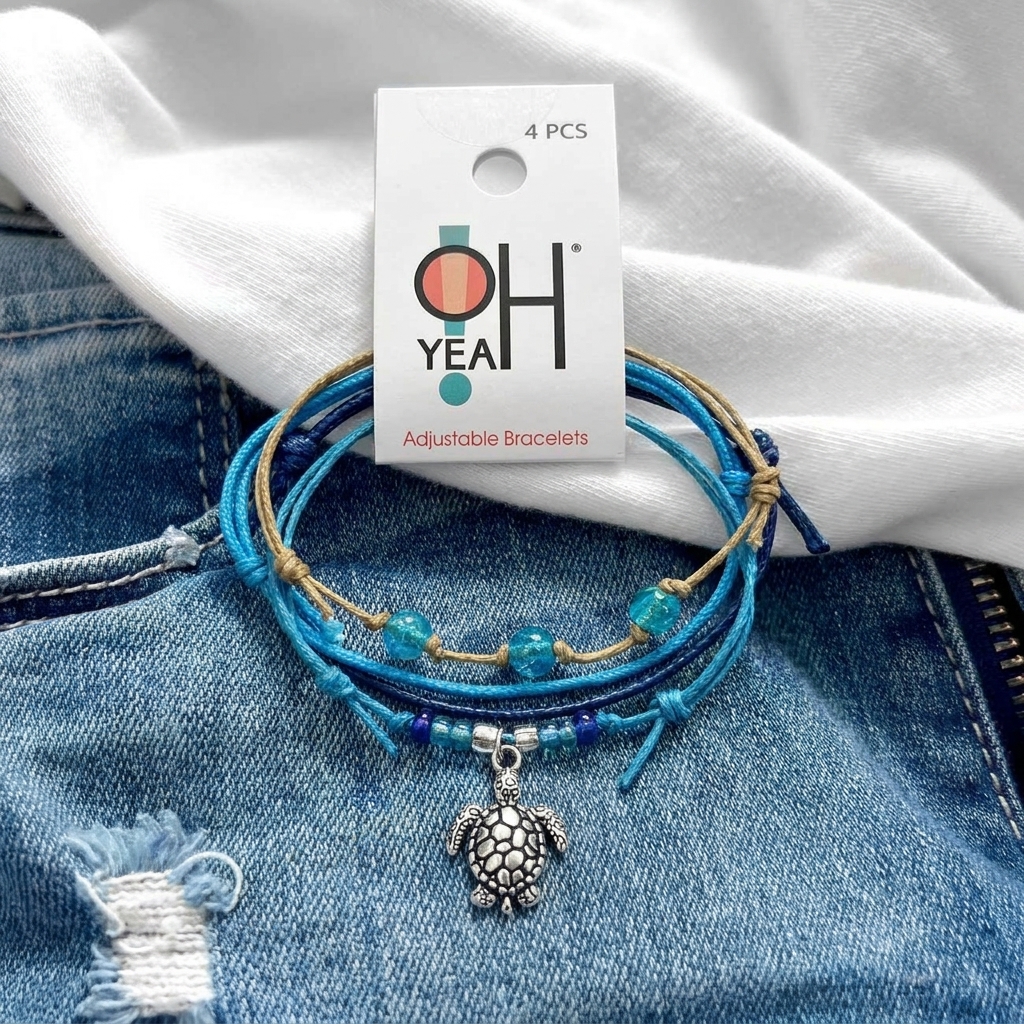 sea turtle bracelet set with blue cords, glass beads and silver turtle charm, O Yeah hang tag on denim and white fabric.
