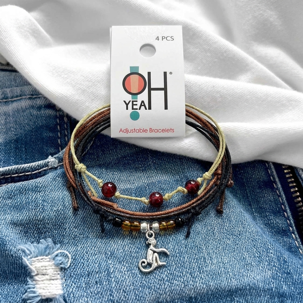 monkey bracelet set on blue denim below a white shirt, with O Yeah tag, dark red beads and silver-tone monkey charm.