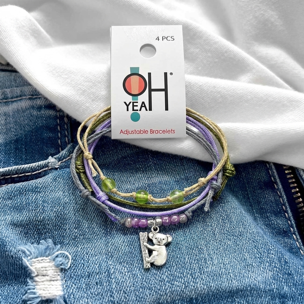 koala bracelet pack with O Yeah tag, purple and green beads, gray and lavender cords and silver-tone charm on blue denim.